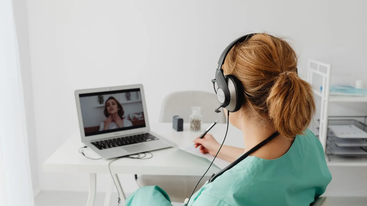 A female doctor conducts a virtual patient consultation via video call.
