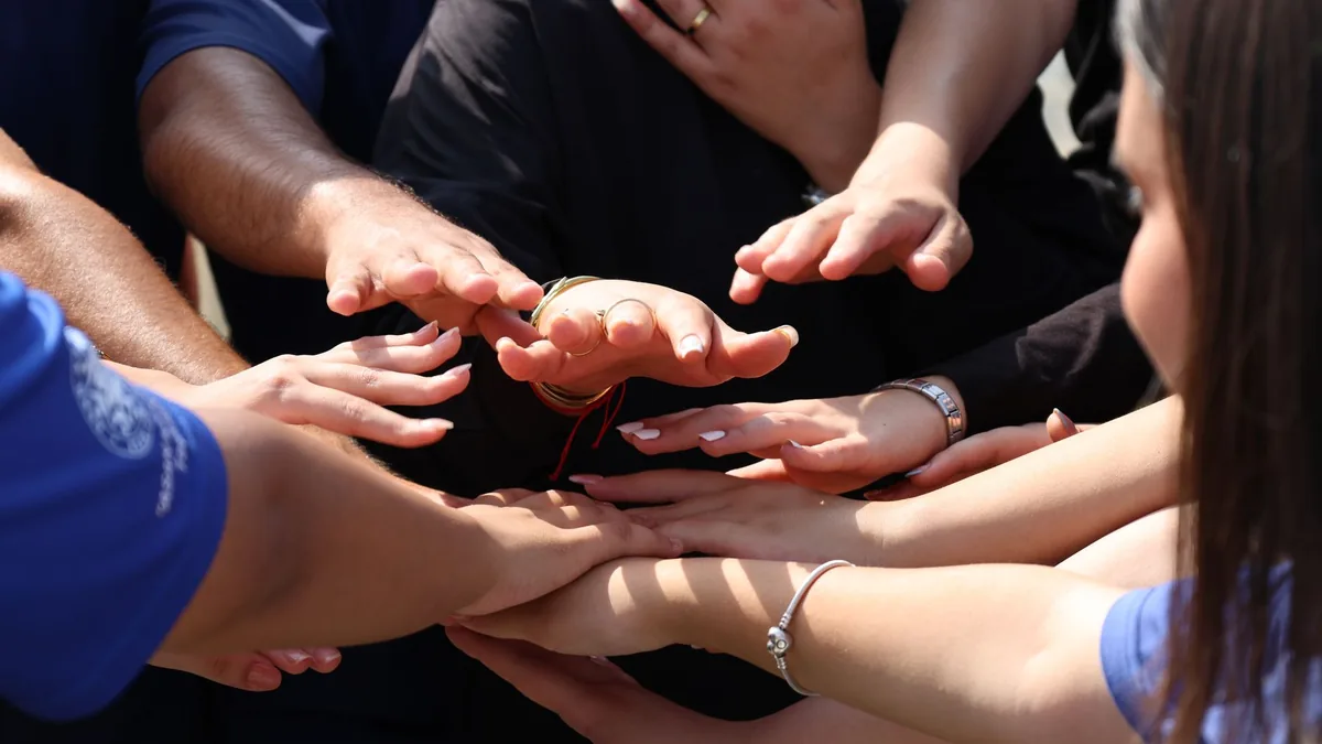 Hands coming together in a circle.