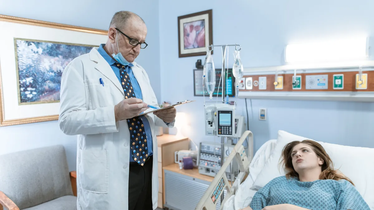 Physician reviewing a patient chart at the bedside in a hospital room